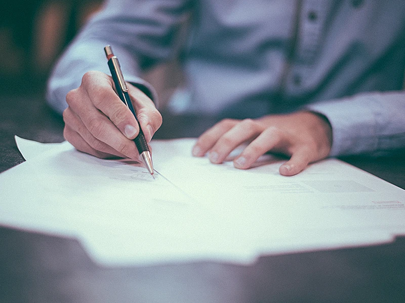 Une personne écrit sur du papier avec un stylo.