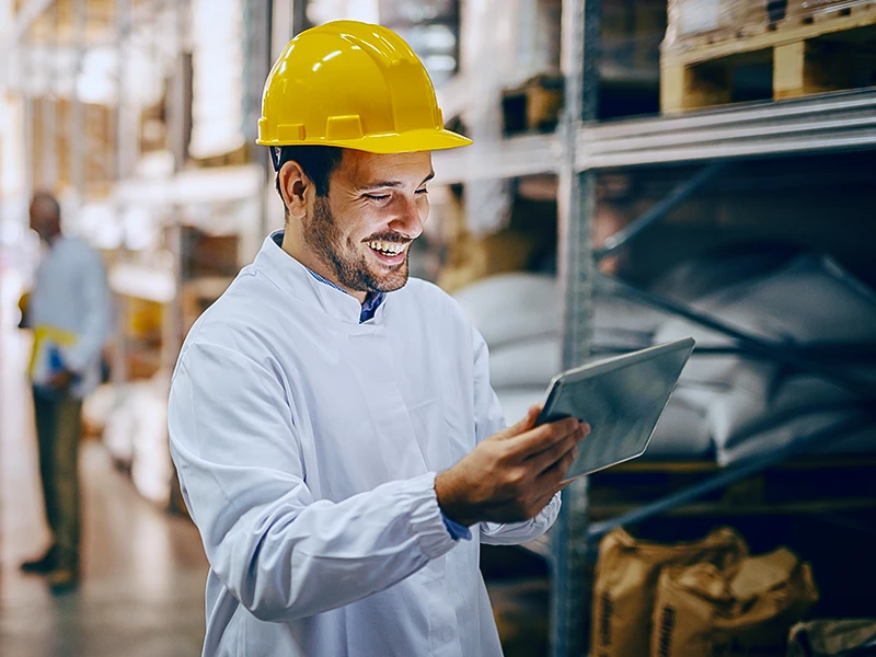 Eine externe Fachkraft für Arbeitssicherheit nutzt iManSys zufrieden auf einem Tablet beim Klienten vor Ort im Lager.  