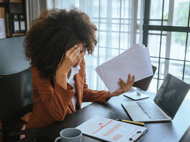 A woman works at a desk and holds her head in despair.